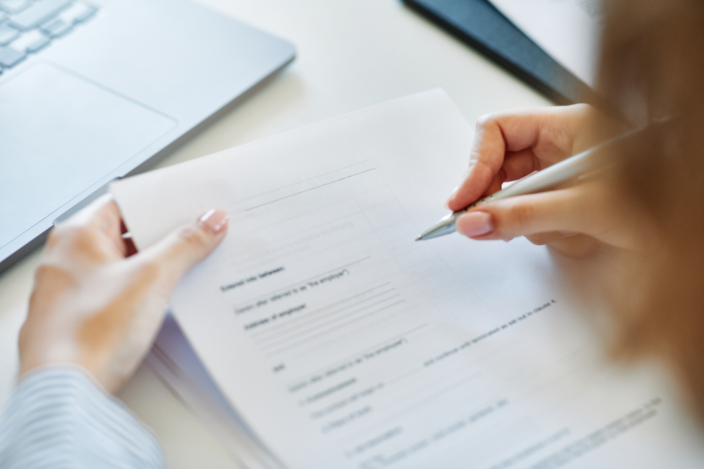 A group of four professionals, two men and two women, are gathered around a conference table reviewing printed charts and documents.